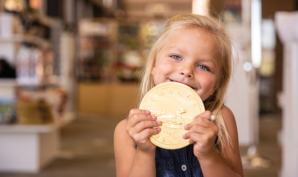 Photo of young girl holding a large gold coin. Photo of young girl holding a large gold coin.