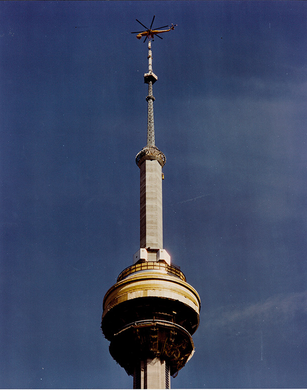 Helicopter placing CN Tower antenna during construction, 1975