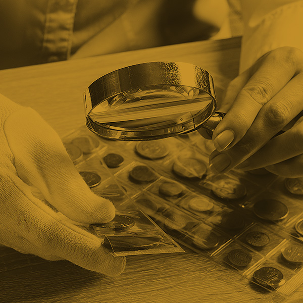 Photo of magnify glass in hand, looking at a coin collection. Photo of magnify glass in hand, looking at a coin collection.